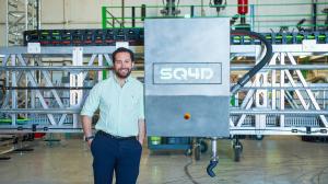 Aiman Hussein standing next to an ARCS construction 3D printer