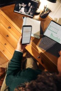 Person using an AI assistant on a smartphone beside a laptop.