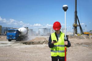 Field manager in high-visibility gear inspecting a construction site, checking safety procedures and compliance documentation during an active site inspection.