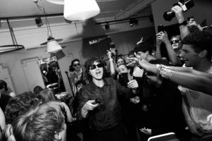 A black and white shot of Bad Nerves in a crowd of fans at the first installment of Tomorrow's Tracks in a small Nudie Jeans store in Soho, London.