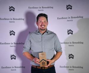 James Massey smiles while holding the 2026 Building Industry Association of Washington (BIAW) Excellence in Remodeling Award for Residential Interior Design in front of the Excellence in Remodeling Awards backdrop.