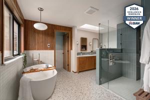 Award-winning Mid-Century Modern bathroom remodel in Sammamish by Tacoma-based design-build remodeling company Massey Remodel + Design, featuring a freestanding soaking tub, terrazzo flooring, vertical wood paneling, skylight, custom vanity, and walk-in g