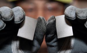Technician holding two rare earth permanent magnet components for quality inspection in a manufacturing environment.