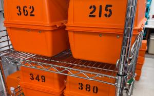 Numbered orange EMS drug boxes staged on a storage rack during a countywide medication recall exchange.