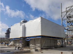 Large industrial module wrapped in custom industrial shrink wrap at an industrial construction site.