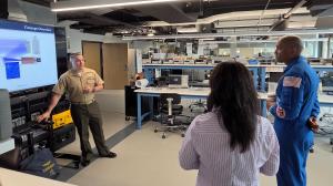 U.S. Marine Corps Lt. Col. Brian Neri, left, a former AV-8B Harrier pilot graduating from the space systems operations curriculum at the Naval Postgraduate School, briefs U.S. Navy Capt. Victor Glover about his thesis research.