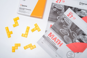 Eye Level Critical Thinking Math booklet with yellow hands-on learning tools arranged on a white surface.