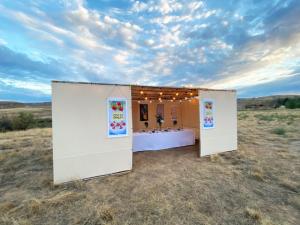 A photo of a large 12x20 sukkah in the high desert of Colorado, with the table set inside and decorations adorning the walls.