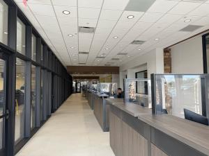 The new service advisor check-in area at Vic Vaughan Toyota of Boerne — a long row of modern wood-grain service desks with individual glass partitions and Dell workstations, set along a bright, polished-tile corridor. A service advisor works at one statio