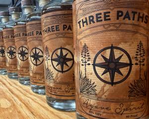 A line of beautifully labeled bottles containing the Three Paths agave spirit.