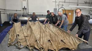 The Margaret's the Couture Cleaner Conservation Team and Chau Thuy, President of the Vietnamese Heritage Museum, presenting the completed, hand-restored historic canvas and bamboo sail from the "Boat of Hope."