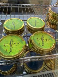 Close-up of Altima Caviar tins in a refrigerated display case at Fiora’s Bottle Shop