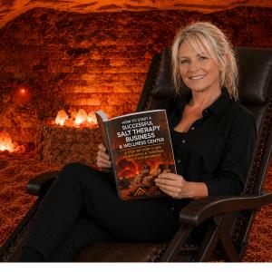 Dr. Margaret Smiechowski inside an authentic Himalayan salt cave, presenting her "Successful Salt Cave" catalog on professional salt room design and salt therapy.