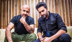Vishal & Sheykhar seated together in a promotional image for their 2026 U.S. concert run, “The Superhit Tour,” supported in select markets by Kash Patel Productions.