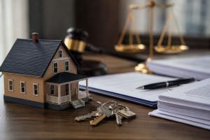 Close-up of a model home, house keys, legal documents, pen, gavel, and scales of justice on a professional desk, representing foreclosure investor transaction review and homeowner equity protection.
