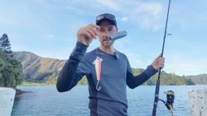 Angler holding CHASING CanFish Fishing CamX mounted with a fishing lure