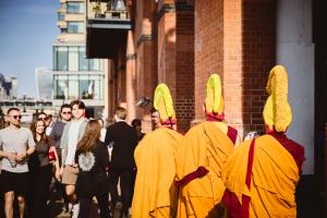 Three senior visiting Tibetan monks leave Oxo Gallery following the ceremonial dissolution of the sand mandala, ahead of the sand’s release into the Thames.