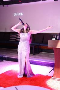 Farrah Mechael performs live on stage in a silver evening gown during the inaugural Peace Gala in Palm Beach, singing before accepting her Ambassador for Peace appointment.