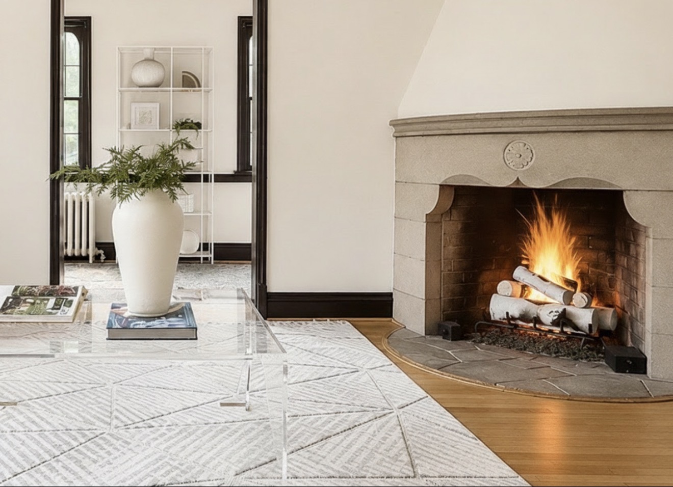 Historic living room featuring a stone fireplace, acrylic coffee table, neutral area rug, and luxury home staging by Jsquared Interior Staging & Design.
