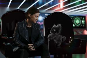 A proof of concept photo showing the bridge of a spaceship. El sits in her captain's chair next to Nugget, a fluffy lyra. Nugget is a black fluff ball. She looks like a cross between a baby goat, a cat, and a rabbit. They are standing with her paws on the arm.