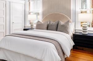Luxury staged primary bedroom designed by Jsquared Interior Staging & Design featuring layered neutral bedding, upholstered headboard, fluted accent wall, and hardwood flooring.