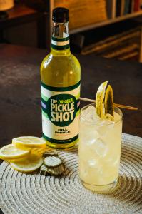 An image of The Original Pickled Lemonade cocktail, with a bottle of The Original Pickle Shot pickle-flavored vodka.