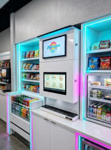 TendedBar Countertop Craft Beverage System with branding display and interactive touchscreen menu, installed between snack shelves and refrigerated coolers in an unattended retail micro-market