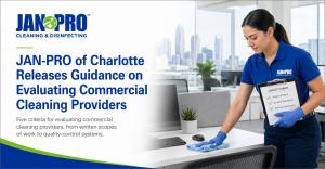 A JAN-PRO Cleaning & Disinfecting professional servicing an office workstation while holding a quality-control checklist, illustrating commercial cleaning provider evaluation in Charlotte.