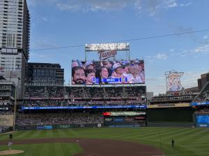 Image of the Jumbotron at Target Field, Minneapolis with US United Unity Seats guests and logo