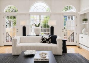 Luxury staged living room in Richmond, Virginia featuring a curved boucle sofa, sculptural coffee table, oversized abstract artwork, black fireplace surround, and modern designer furnishings.