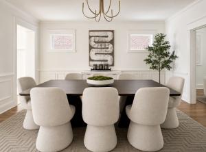 Luxury dining room with oversized dark wood table, boucle dining chairs, contemporary chandelier, abstract artwork, and designer staging in Richmond, Virginia