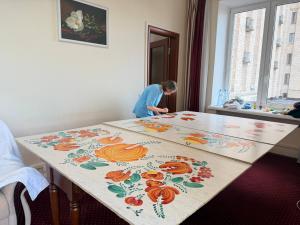 Liubava Malitska paints a wooden art panel covering a window damaged by a Russian strike at Hotel Ukraina in Kyiv.