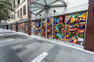 mural on plate-glass window with iconic Houston imagery, astronauts, cowboys, industrial workers, Latina women in brightly colored dress