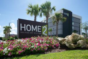 Exterior of Home2 Suites by Hilton Fort Walton Beach at Freedom Tech Center with hotel signage, landscaping, and palm trees.