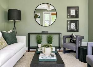 Professionally staged living room in Richmond, Virginia featuring sage green walls, white sofa, charcoal accent chairs, modern artwork, and luxury home staging by Jsquared Interior Staging & Design.