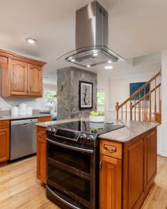 Open-concept kitchen with granite countertops, wood cabinetry, stainless steel appliances, center island, and stone accent wall professionally prepared for listing photography.