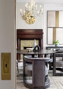 Professionally staged luxury dining room with a round dining table, sculptural chairs, fireplace, statement chandelier, and contemporary artwork.