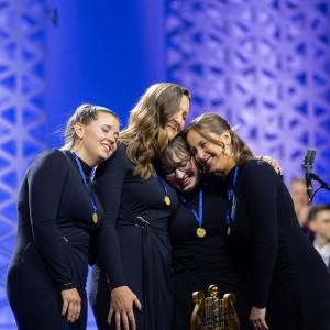 Four women smiling wearing champion medals