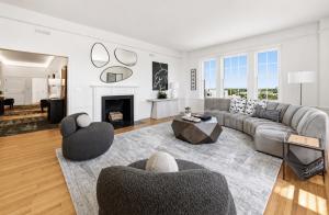 Staged living room at The Prestwould Richmond VA by Jsquared Interior Staging and Design with curved gray sectional, fireplace, sculptural mirrors, and city views