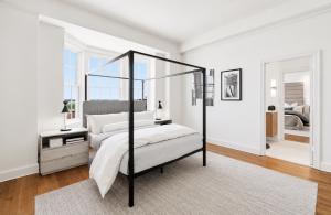 Staged primary bedroom at The Prestwould Richmond VA with black canopy bed, bay window with skyline views, and neutral furnishings by Jsquared Interior Staging and Design