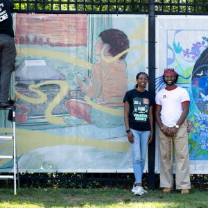 Artists Nile Livingston and De'von Downes stand beside their "Echoes Beyond the Stage" mural installation at the Highmark Mann Center for the Performing Arts in Philadelphia