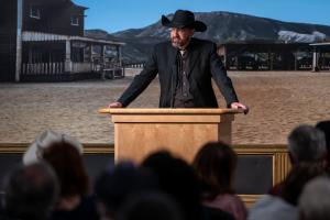 Kellen Cutsforth, Executive Director Western Writers of America, dressed in western attire on stage speaking about the history of the Western story as America's contribution to literature.