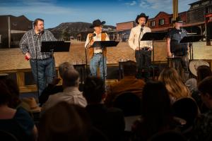 Performance of "The Reign of the Gila Monster" by (l to r) Travis Oates, Bob Caso, Richard Reich, and R.F. Daley standing on the stage in costume.