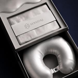 Silver silk travel neck pillow and matching accessory displayed in a black SENSOIRE gift box.