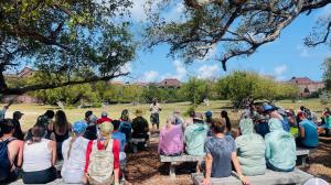 A tour group sits on stone benches and listens to a tour guide describe Fort Jefferson, a large brick fort.