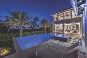 Gulf-front Naples luxury residence at dusk with an infinity pool, palm trees and open outdoor living space.