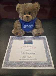 BARE International mascot beside the 2026 MSPA Americas Shoppers' Choice Award certificate.