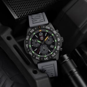 Luminox Pacific Diver Chronograph 3140 Graphite Grey watch with illuminated Luminox Light Technology (LLT) displayed alongside tactical gear in a low-light setting.