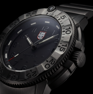 Close-up of the Luminox Navy SEAL Foundation XS.3228.NSF watch showing the IP Gun stainless steel bezel, blackout dial, luminous hands and engraved crown.