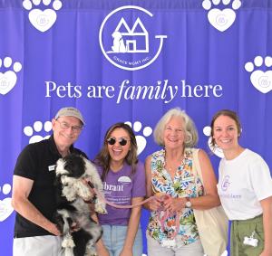 Four people pose with an adorable black-and-white dog at The Highlands Pets Are Family Here™ launch.